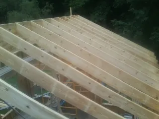 New roof rafters set over an addition before sheathing in Grey Eagle