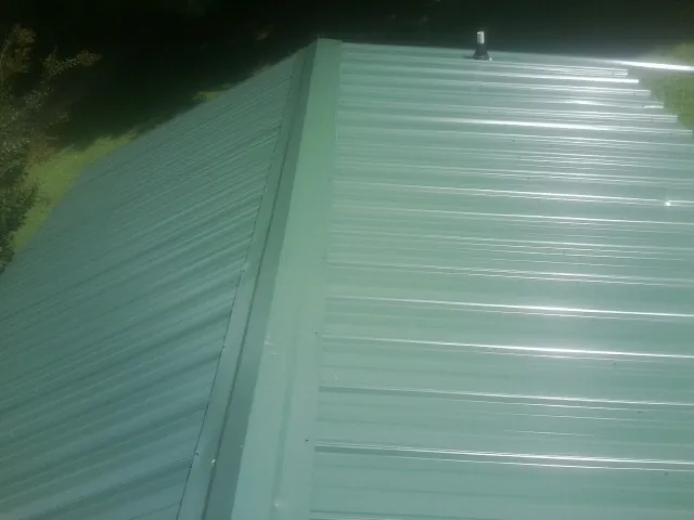 New green metal panels meeting at the ridge of a roof — Flat Roof Repair work by our crew in Grey Eagle