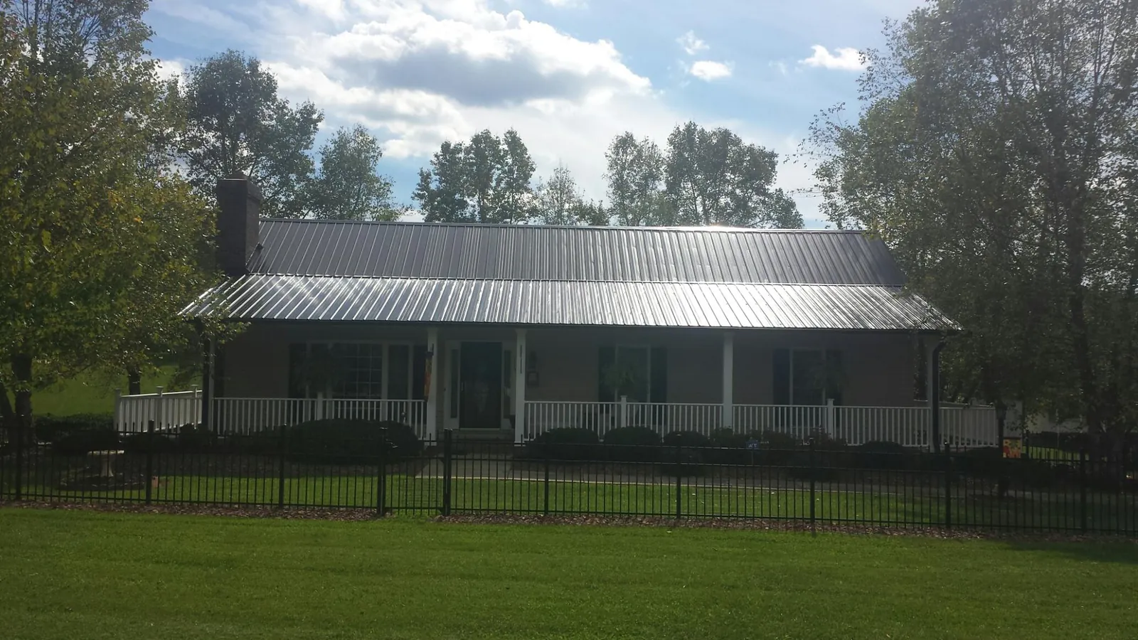 Gray metal roof on a brick ranch with a full width front porch — Gutter Guard Installation work by our crew in Grey Eagle