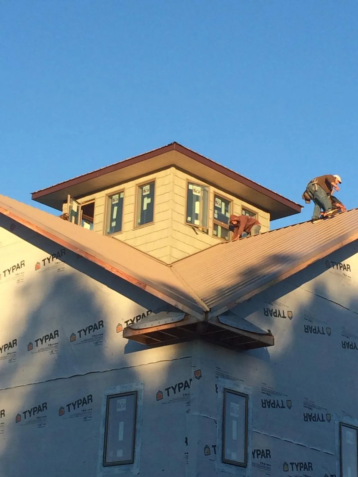 Roofers working around a rooftop cupola on a new metal roof at sunset — Roof Waterproofing in Grey Eagle by Roofing Brothers